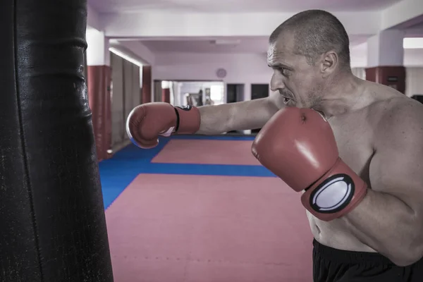 Muay thai luchador golpear la bolsa pesada en el gimnasio —  Fotos de Stock