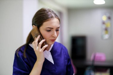 Temizlik servisi üniformalı kadın cep telefonu kullanıyor.