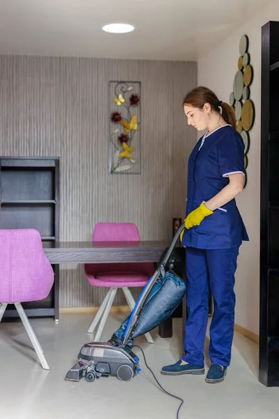 Young Female Maid Cleaning Floor With Vacuum Cleaner