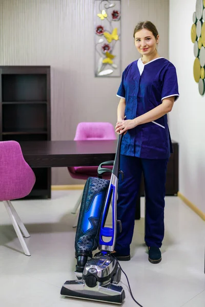 Young Female Maid Cleaning Floor With Vacuum Cleaner