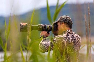 Kamuflaj kıyafetli profesyonel vahşi yaşam fotoğrafçısı.