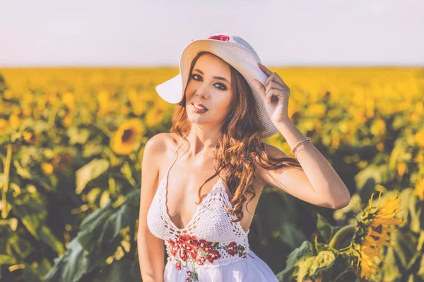 在阳光明媚的夏日 美丽的女人拿着向日葵在农田里摆姿势 — 图库照片