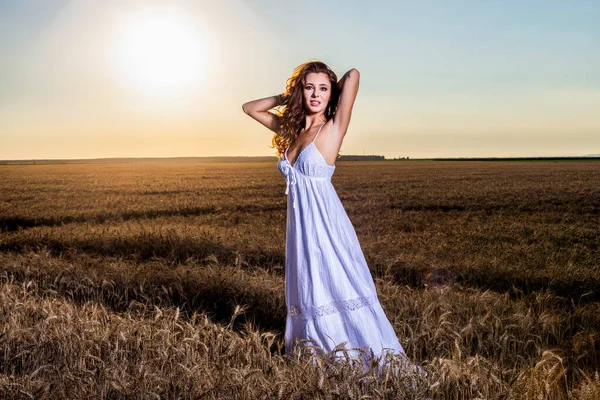 一个美丽的女人 穿着白色的衣服 日落时分在麦田里 — 图库照片