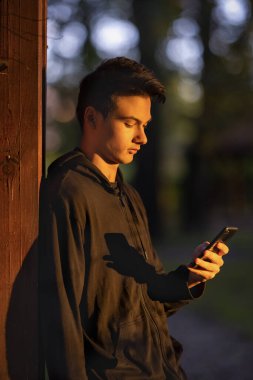 Güz parkında cep telefonu olan genç bir adam.