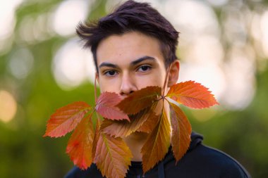 Yaprak maskeli genç bir adamın sonbahar portresi