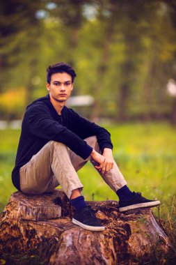 Sonbahar doğal ortamında sonbahar kıyafetleri içinde genç ve yakışıklı bir adam.
