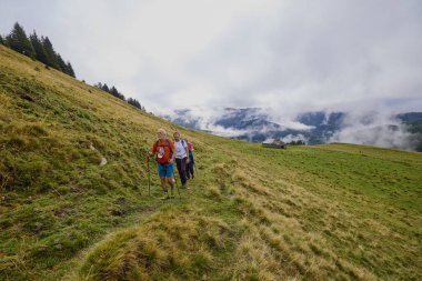 Bulutlu ve sisli bir günde büyükbabalarıyla dağlarda yürüyen bir çift..