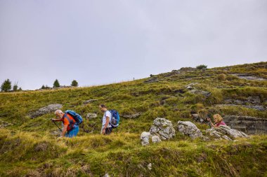 Bulutlu ve sisli bir günde büyükbabalarıyla dağlarda yürüyen bir çift..
