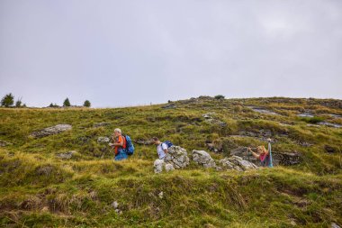 Bulutlu ve sisli bir günde büyükbabalarıyla dağlarda yürüyen bir çift..