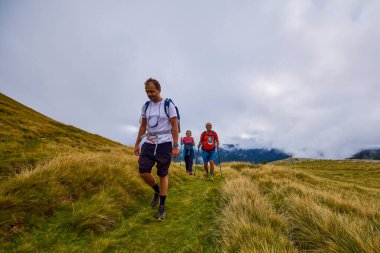 Bulutlu ve sisli bir günde büyükbabalarıyla dağlarda yürüyen bir çift..