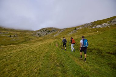 Bulutlu ve sisli bir günde büyükbabalarıyla dağlarda yürüyen bir çift..