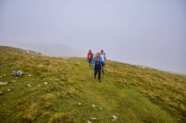 Bulutlu ve sisli bir günde büyükbabalarıyla dağlarda yürüyen bir çift..