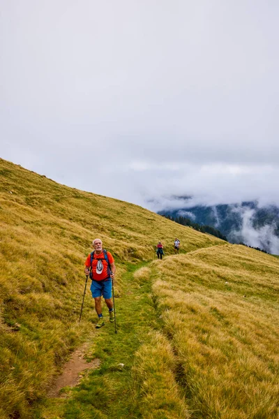 Bulutlu ve sisli bir günde büyükbabalarıyla dağlarda yürüyen bir çift..