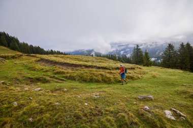 Güçlü yaşlı bir adam bulutlu bir günde dağa tırmanıyor.
