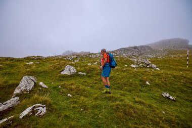 Güçlü yaşlı bir adam bulutlu bir günde dağa tırmanıyor.