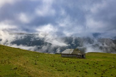 Romanya 'nın Bucegi Dağları' nda terk edilmiş ahşap ağılı dağ manzarası bulutlu bir Eylül gününde