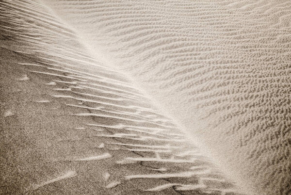 sand and wind patterns on dune surface. Pattern is formed by two types of sand grains - dark, small and lightweight and larger lighter and heavier ones. Maspalomas, Gran Canaria, Canary Islands, Spain