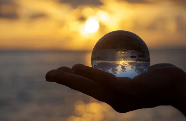 Crystal ball photography - sunset beach, hand holding the ball