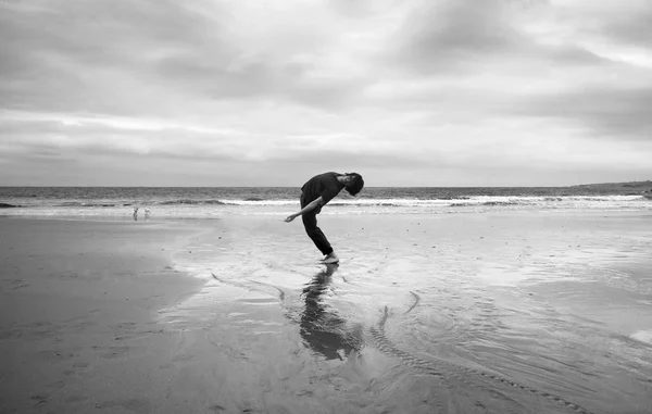 Νεαρός Άνδρας Μια Υγρή Αμμώδη Παραλία Κάνει Ακροβατικά Μονόχρωμη Εικόνα — Φωτογραφία Αρχείου