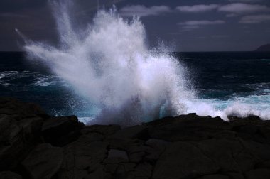 Gran Canaria 'nın kuzey kıyısı, Kanarya Adaları, dalgalar Banaderos bölgesindeki karanlık kayalara çarpıyor.