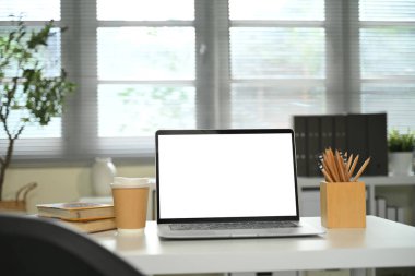 Ofis masasında boş ekranlı dizüstü bilgisayar, kahve fincanı ve kalem tutacağının yanında..
