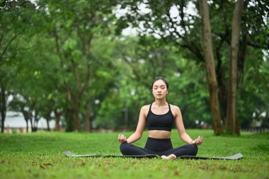 Spor giyimli kadın sporcu yoga yapıyor ve doğada bilinçli meditasyon yapıyor..