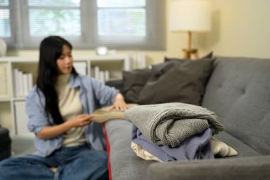 Katlanmış kazaklar ve elbiseler düzgünce kanepeye istiflenmiş ve seyahat için paketlenmiş bir kadın..