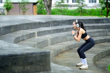 Parkta spor yapan bayan sporcu, taş basamaklarda vücut ağırlığı egzersizi yapıyor..