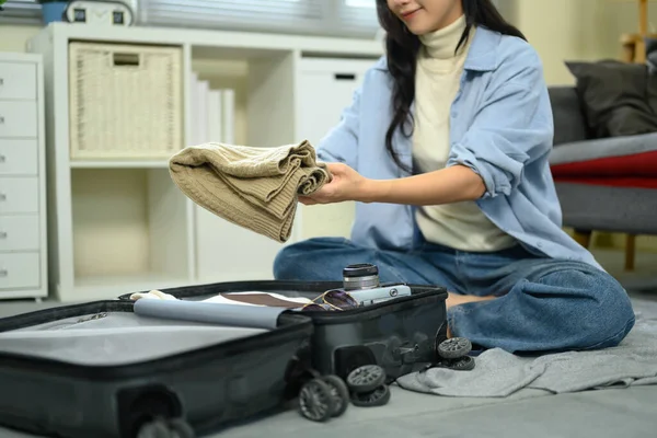 Yolculuk için hazırlanırken genç bir kadın bavulunu bavula koyuyor..