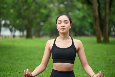 Kadın parkta meditasyon yapıyor ve yoga yapıyor..