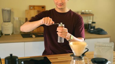 Modern bir mutfakta el değirmeniyle kahve çekirdeklerini öğüten adam..