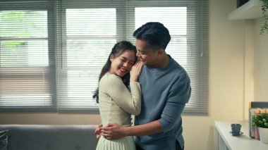 Mutlu çift evde sevgiyle sarılıyor, sıcak ve samimi bir anın tadını çıkarıyorlar..