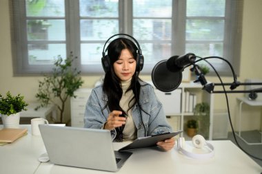 İçerik yaratıcısı modern bir ev ofisinde tablet ve mikrofon kullanarak canlı yayın yapıyor..