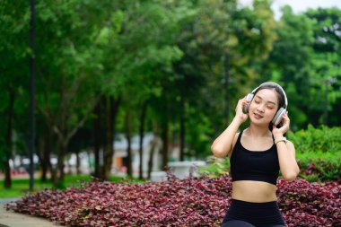 Rahatlamış bayan sporcu ara veriyor ve doğada müzik dinliyor..