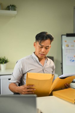 Ofiste çalışırken önemli iş belgelerini düzenleyen odaklı bir adam.