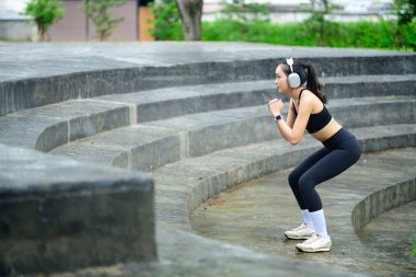 Şehir parkındaki taş basamaklarda çömelme yapan bir sporcu. Sağlıklı yaşam tarzı kavramı.