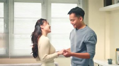 Mutlu genç çift evde dans ediyor ve neşeli, neşeli bir anın tadını çıkarıyor..