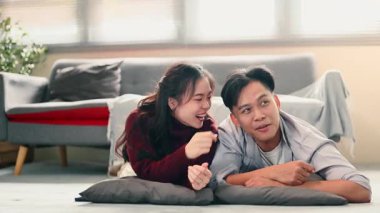 Oyuncu genç çift yerde yatıyor, gülümsüyor ve evde birlikte hassas bir anın tadını çıkarıyorlar..