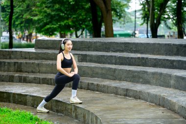 Doğal bir kentsel ortamda esneme rutiniyle kardiyo seansına hazırlanan sporcu.