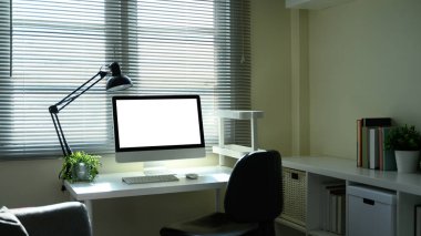 Masaüstü bilgisayarı, ofis sandalyesi ve pencere kenarında saksı bitkisi olan parlak çalışma alanı.