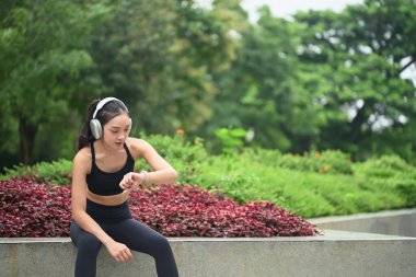 Antrenman sırasında ara veren bayan sporcu, Smartwatch 'taki fitness verilerini izliyor.