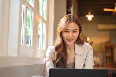 Dijital göçebe konsepti, kafede laptopuyla çalışan Asyalı kadın..