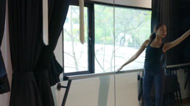 Kadın, modern bir dans stüdyosunda bale pozu, denge ve zarafet gösterisi yapıyor..