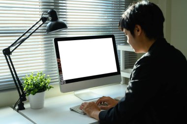 Merkez ofisteki boş beyaz ekranlı masaüstü bilgisayarı üzerinde çalışan adam.