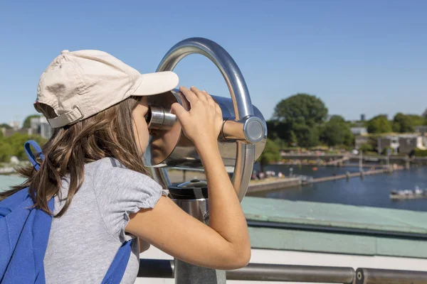 The girl looks with interest at the telescope