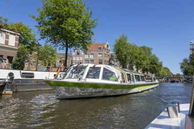 Amsterdam, Hollanda - 2 Temmuz 2018: Amsterdam merkezindeki Amstel Nehri üzerindeki turizm gemisi