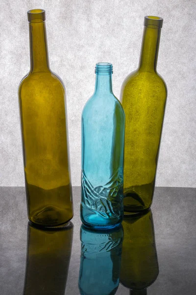 Stilleven Met Drie Gekleurde Glazen Flessen Een Grijze Achtergrond — Stockfoto