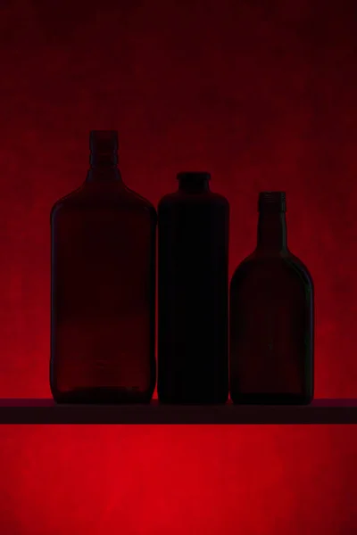 Stilleven Met Silhouetten Van Flessen Een Rode Achtergrond — Stockfoto