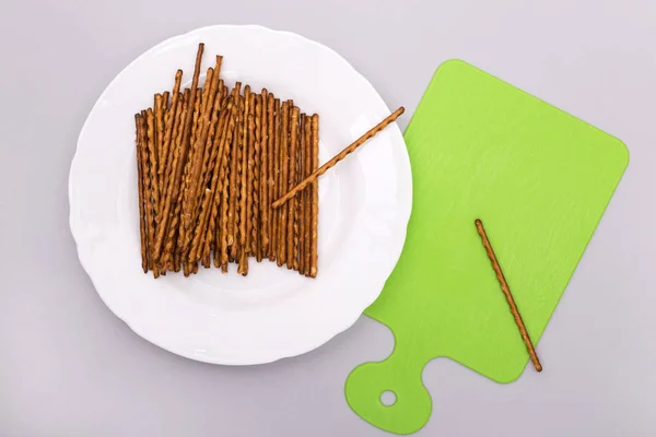 Salty sticks on a white plate, top view