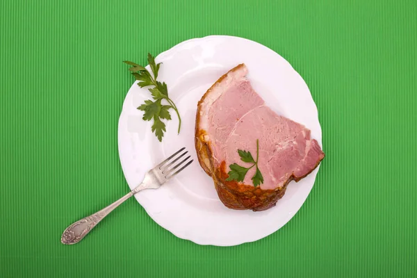 緑の背景にプレートの新鮮な豚肉ハムの大部分 — ストック写真